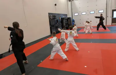 Instructor assisting children during martial arts practice