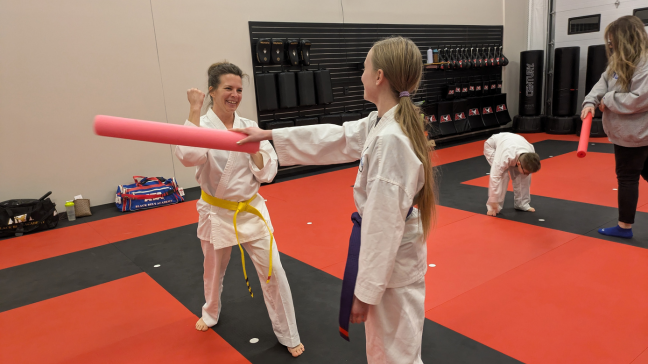 Student training with a foam noodle in martial arts class