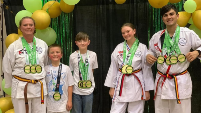 Group of martial arts students smiling and posing with medals